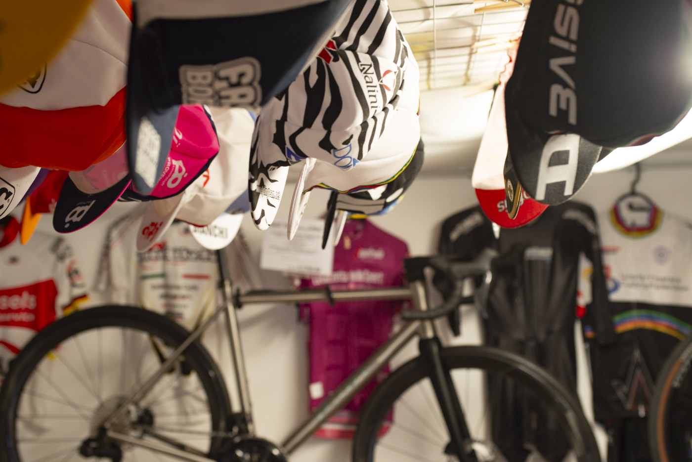Cycling caps hanging in front of the Pilot Celes titanium road bike